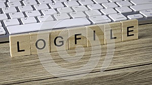 LOGFILE Word Spelled Out on Wooden Blocks Placed on Keyboard Representing IT Debugging and System Records