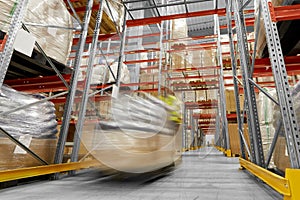 Worker carrying loader with goods at warehouse