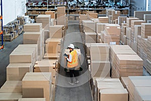 Logistic warehouse worker delivering boxes on a trolley.