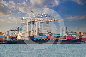 Logistics and container loading by large barges by sea in a harbor full of containers waiting to be transported