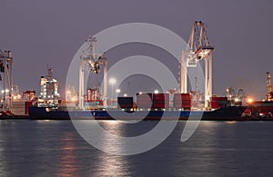 Logistics and container loading by large barges by sea in a harbor full of containers waiting to be transported