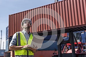 Logistics engineer working with computer and looking Shipping containerin commercial transport port