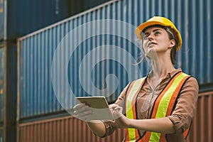 The logistics female staff is standing in front of colorful containers at habour warehouse, Supply chain and logistics concept