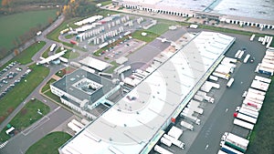 Logistics park with a warehouse and loading hub. Semi-trucks with cargo trailers standing at the ramps for loading/unloading goods