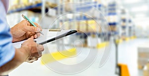 logistics service man writing documents on clipboard in warehouse