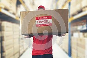 Logistics warehouse worker holding package with fragile items photo