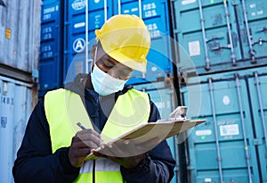 Logistics worker, container port and covid, black man writing on inventory checklist. Cargo yard, export and safety for