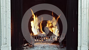 Logs burning on fire into fireplace with marble and stone, the crackle of a fire and sparks