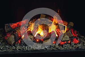The logs of the fireplace burn with a bright fire. Artificial decorative fireplace