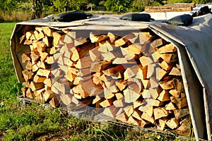 Logs of firewood chopped on logs in woodpile, logging for winter, concept stoking stove, fireplace, seasonal cooling in housing,