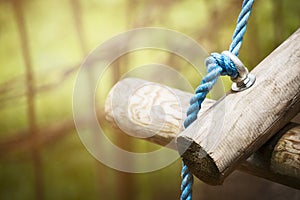 Logs on rope bridge in climbing forest or high wire park on nature sunny background, close up