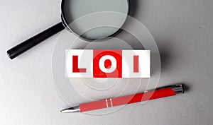 LOI word on wooden cubes with pen and magnifier