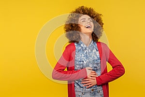 Lol, hilarious joke! Portrait of woman with curly hair in casual outfit holding her belly and laughing