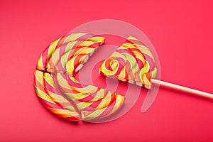 Lollipop broken into pieces on pink background, top view with copy space