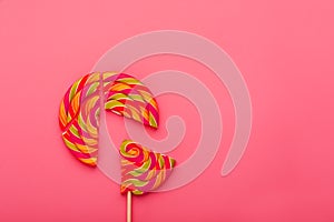 Lollipop broken into pieces on pink background, top view with copy space