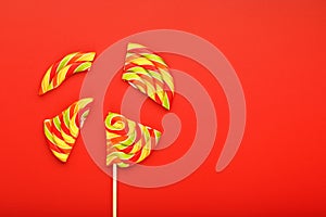 Lollipop broken into pieces on red background, top view with copy space
