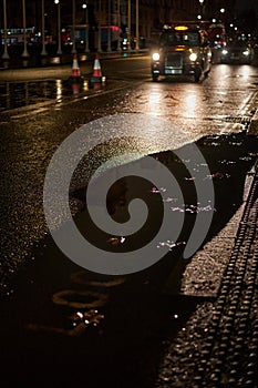 London black cab on wet road with large puddle