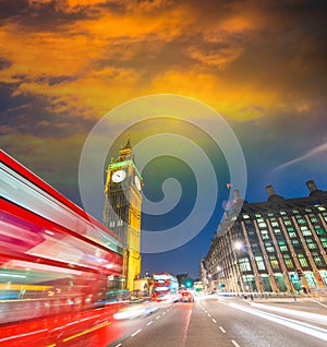 London. City night scene with red bus crossing Westminster. Traffic light trails