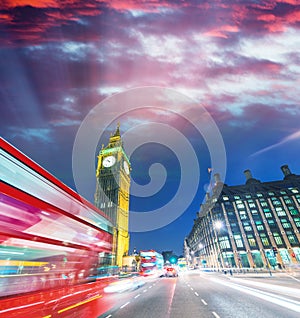 London. City night scene with red bus crossing Westminster. Traffic light trails