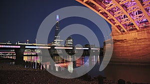 London city skyline with lights lit up at night on the River Thames beach at low tide looking at the