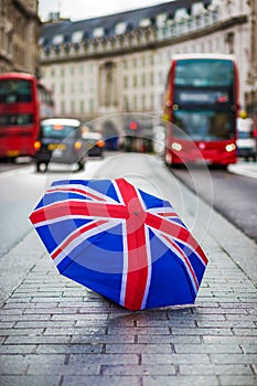 London, England - British umbrella at busy Regent Street with iconic red double-decker buses and black taxi