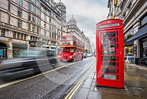 London, England - Iconic blurred black londoner taxi and vintage red double-decker bus on the move