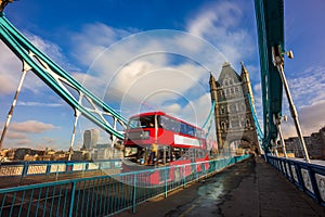 London, England - Iconic red double-decker bus in motion on famous Tower Bridge