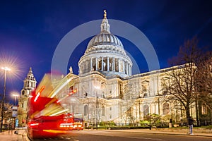 London, England - The Saint Paul`s Cathedral with famous old red double decker buses on the move