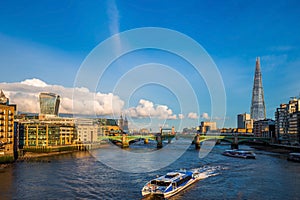 London, England - Sightseeing boats at sunset on River Thames with Southwark Bridge and Tower Bridge