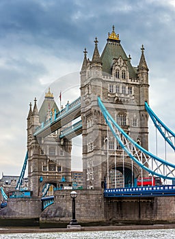 London, England - Tower Bridge, the icon of London on a cloudy morning with traditional red double-decker bus