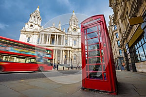 London, England - Traditional red telephone box with iconic red double-decker bus on the move at St.Paul`s Cathedral