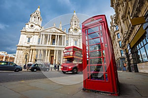 London, England - Traditional red telephone box with iconic red vintage double-decker bus on the move