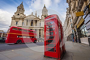 London, England - Traditional red telephone box with iconic red vintage double-decker bus on the move