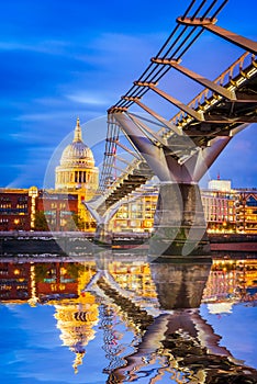 London, England - United Kingdom. St Paul Anglican dome and Millennium Bridge, early in the evening twilight Thames River