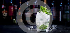 London Mint Swizzle alcohol cocktail drink with dry gin, lemon juice, sugar syrup, soda, mint and ice. Black bar counter