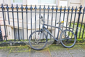 London - old bicycle leaning against wrought iron fence outside building with bay window well in background - selective focus