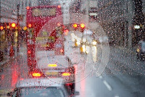 London rain view to red bus through rain-specked window