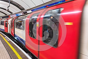 London tube platform edge. Painted warning on the floor. Train passing by.