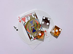 London, UK - April 2020: Ace of Spades and Jack of Hearts in a hand of blackjack alongside some casino dice