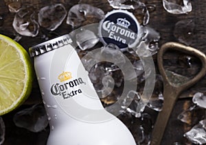 LONDON, UK - APRIL 27, 2018: Steel Bottle of Corona Extra Beer on wooden background with bottle opener and ice cubes.Top view