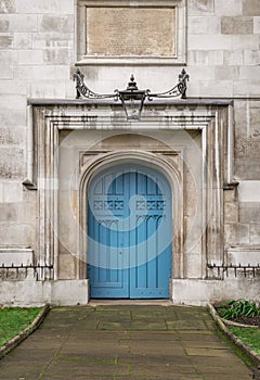 Arched medieval door with a lantern above it. Details of Closed blue wooden church doorway in a gothic stone wall