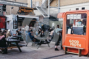 People enjoying street food in Elys Yard street food market in East London, UK