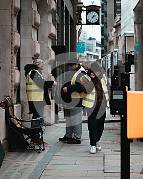 London UK February 2021 Three workers on the streets of London wearing yellow high visibility jackets on duty, one guy having a