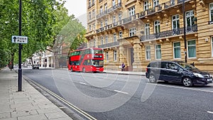 London, UK - July 8, 2020: Modern red double-decker bus passing by Hyde Park Place building in central London