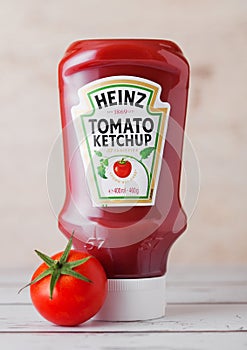 LONDON, UK - MARCH 10, 2018 : Plastic bottle of Heinz Ketchup on wood with raw tomato. Manufactured by H.J. Heinz Company