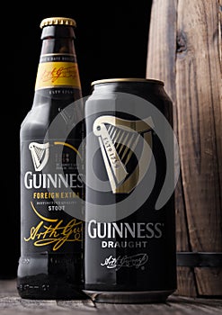 LONDON, UK - MAY 03, 2018: Aluminium can and glass bottle of Guinness draught stout beer next to wooden barrel on dark wooden back