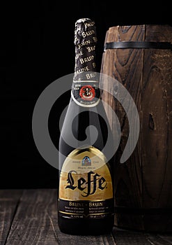 LONDON, UK - MAY 03, 2018: Cold bottle of Leffe beer next to wooden barrel on black background.Leffe is made by Abbaye de Leffe in