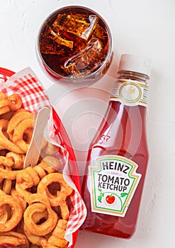 LONDON, UK - SEPTEMBER 10, 2018: Bottle of Heinz tomato ketchup on white kitchen background with glass of cola and curly fries.