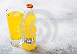 LONDON, UK - SEPTEMBER 28, 2018: Glass and bottle of Fanta Orange soda drink with ice cubes and bubbles on stone kitchen table bac