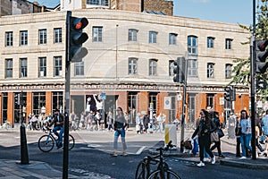 People crossing the road in front of AllSaints shop in Shoreditch, London, UK